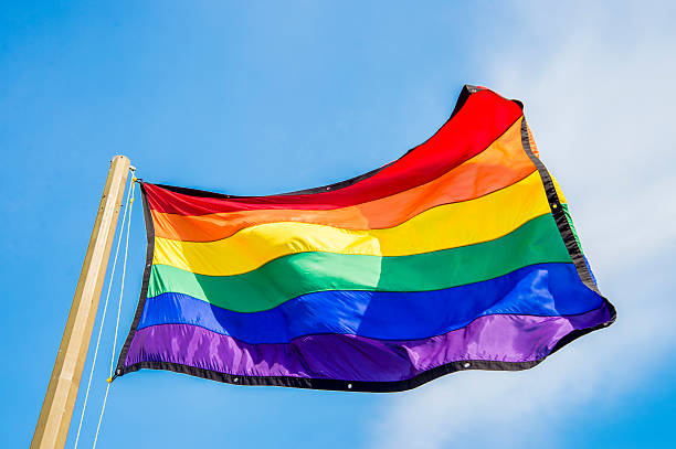 istock Gay rainbow flags waving over blue sky background 506904138