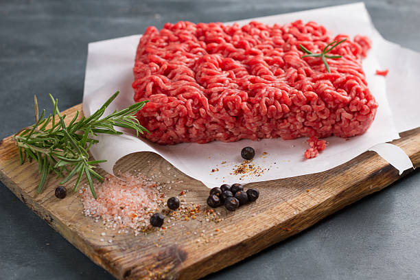 Minced meat on butcher pape Minced meat on butcher paper with basil and pepper, selective focus ground beef photos stock pictures, royalty-free photos & images