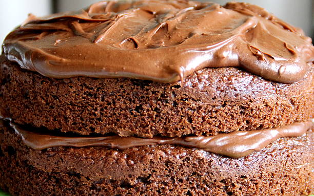 Close up of Homemade Chocolate Cake filled with ganache Close up of Homemade Chocolate Cake topped and filled with chocolate ganache, layered. This photo shows the entire cake from a side profile, the main focus being on the top central section of the photo showing the chocolate sponge and the chocolate ganache spread on the top. The filling lower down and the next section of sponge. Taken with a Canon EOS 1100D Digital Camera. cake texture stock pictures, royalty-free photos & images