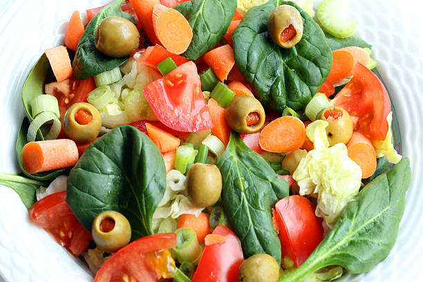 tossed together garden salad of spinach, lettuce, tomato,green onion, celery and olives