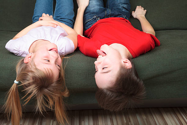 istock Siblings sticking out tongues on a couch 506909678