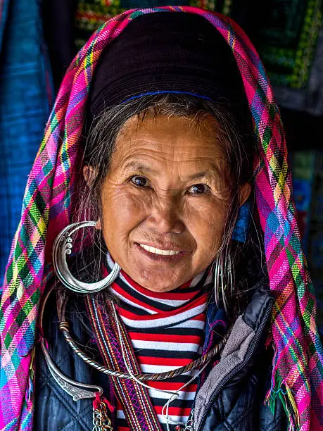Portrait of Black Hmong woman wearing traditional headdress and jewelry at shop in Ban Ho village, near Sapa, North Vietnam.
