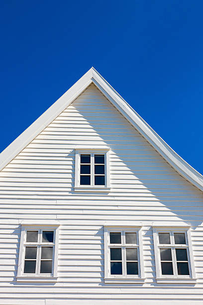 istock White wooden house gable against blue sky 506911612