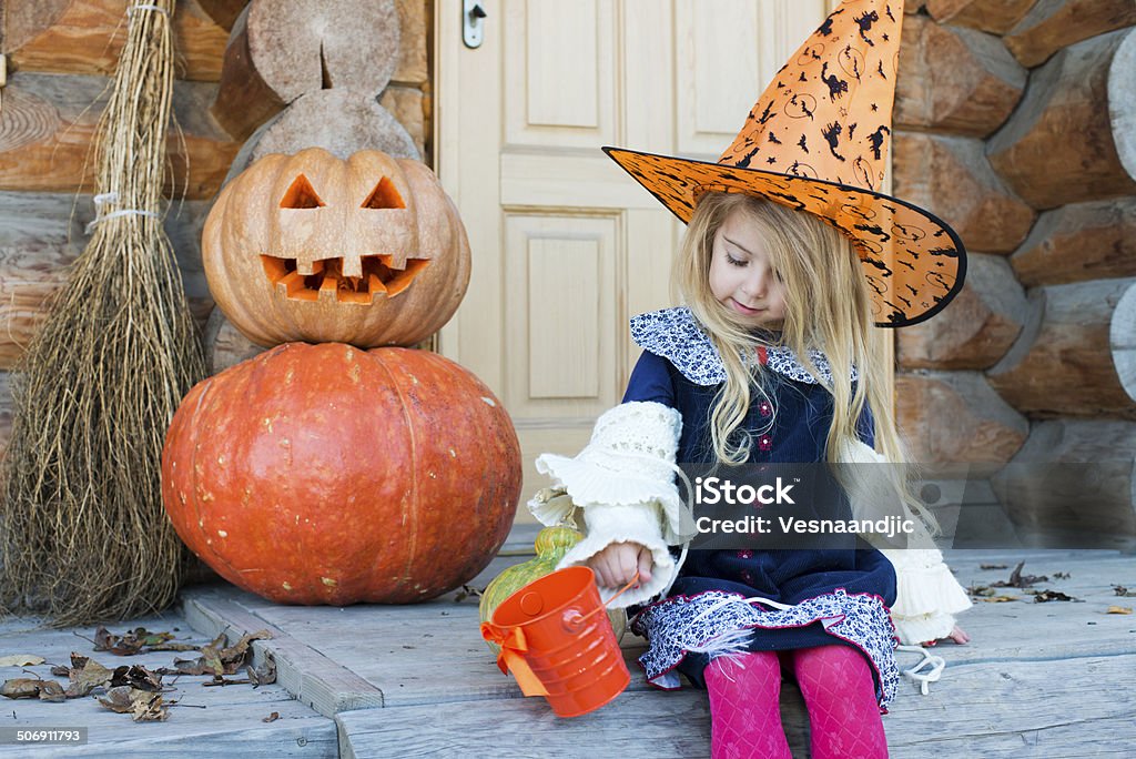 Little witch Cute little girl with witch hat at halloweeen decoration in front of wooden house Blond Hair Stock Photo