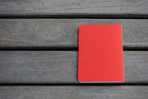 istock red notebook with wooden background 506912038