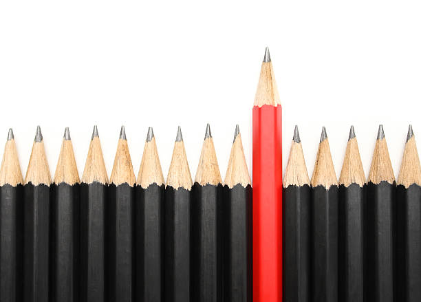 istock Red pencil standing out from identical black fellows. 506913178