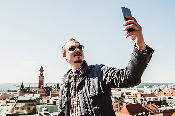 Man taking selfie with smart phone outdoors in city