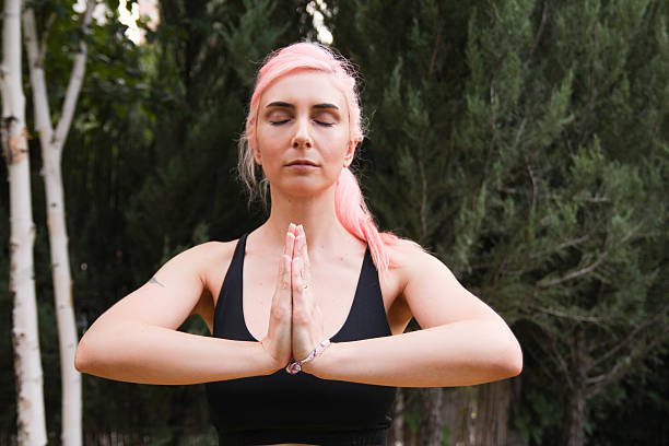 pink haired woman meditating outdoor stock photo