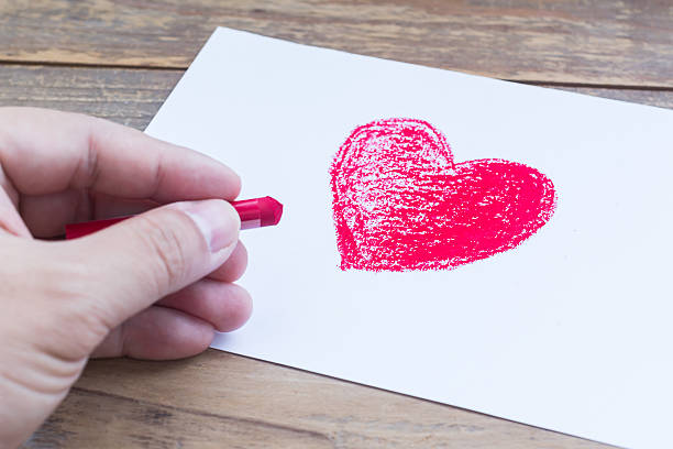 istock Hand draws red heart of crayon on white paper 506919926