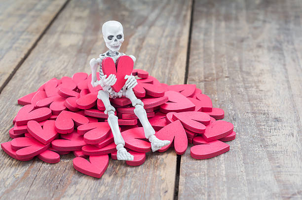 istock Skeleton hold red heart shape on wood table 506920280