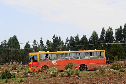 Addis Ababa, Ethiopia-March 24, 2013: Red and yellow painted local bus stops on a side way while waiting for passengers on March 24, 2013. Outskirts of Addis Ababa city-Ethiopia.