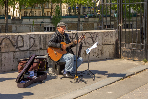 Paris, France - May 3, 2014: Busker sings French chanson with a guitar on the waterfront near Notre Dame in Paris on 3 may 2014.