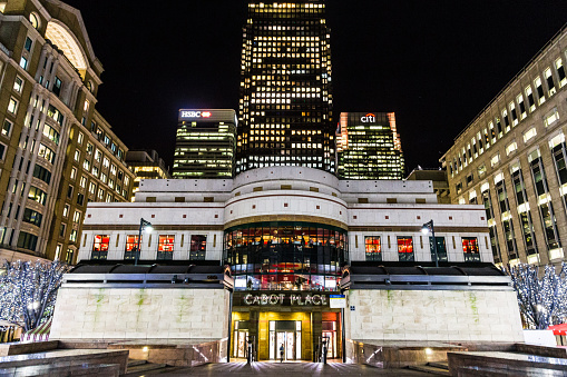 London, UK - December 21, 2015: night view of Cabot Square, which is part of the Canary Wharf development on the Isle of Dogs, London, UK. The square includes a fountain and several works of art, and is the address for the London Offices of Credit Suisse and Morgan Stanley. Cabot Place, on the east side of the square is a large shopping centre, and the square is also home to several restaurants including First Edition, Sri Nam and Corney and Barrow.