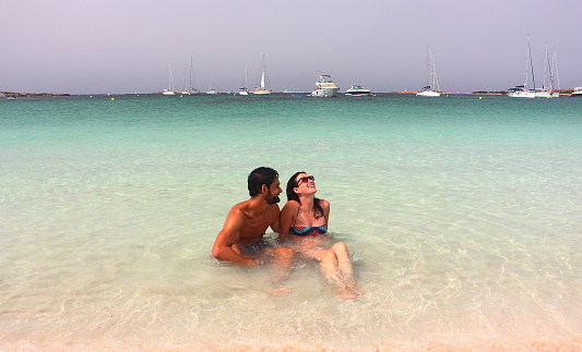 Young beautiful couple enjoys an early morning lonely bath in Espalmador beach, one of the most beautiful spots in Formentera, Balearic Islands, Spain.