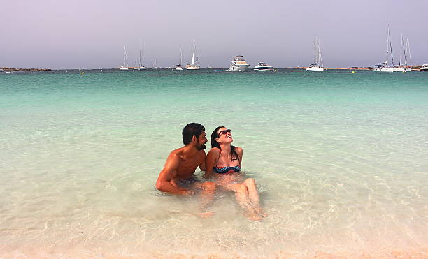 beautiful couple enjoys an early morning lonely bath in Formentera Young beautiful couple enjoys an early morning lonely bath in Espalmador beach, one of the most beautiful spots in Formentera, Balearic Islands, Spain. formentera island stock pictures, royalty-free photos & images
