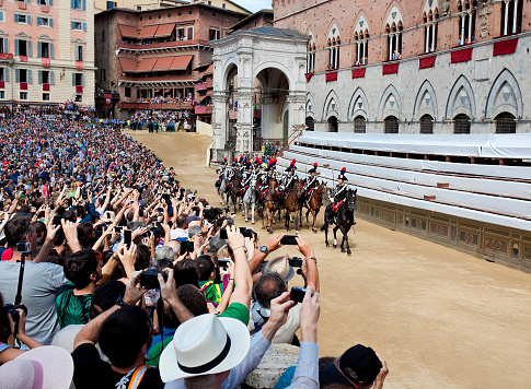 Siena, Italy - August 16, 2014: Performance of cavalry on parade before start of annual traditional Palio di Siena horse race in medieval square \