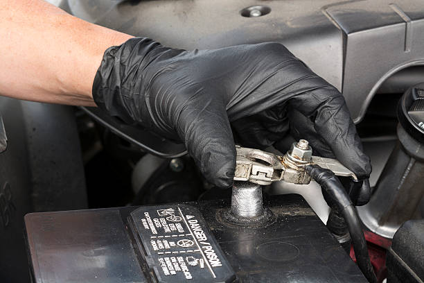 Installing battery terminal A mechanic reinstalls a clean battery terminal using a wrench to secure the cable to the post during routine automobile maintenance. car battery stock pictures, royalty-free photos & images