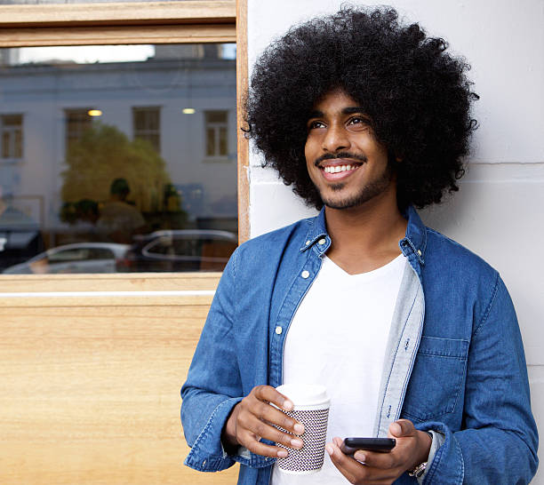 istock Man with afro standing outside with mobile phone ad coffee 506925374