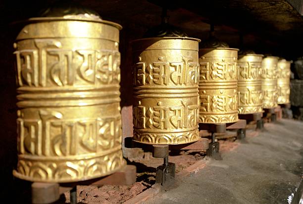 ruote di preghiera buddista dorata - tibetan script foto e immagini stock