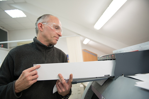 Middle aged man changing toner cartridge at printer's, CMYK colors, small business, occupation, real people