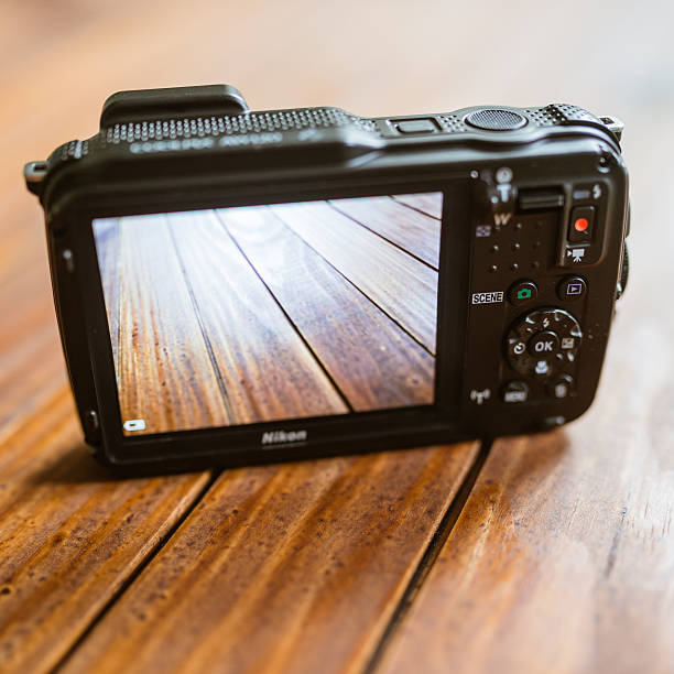 Florence, Italy - August 12, 2014: Close up of the rear of new waterproof nikon coolpix AW 120 (camouflage color) on plank wood. It is the new antishock and waterproof compact camera made by Nikon, released on February 2014. This camera is able to shoot and record up to 18 meters under water, record video on full HD and have a nice GPS to print in any images all the location data. It have also an huge 3 inch LCD screen on the back. Studio shot image.