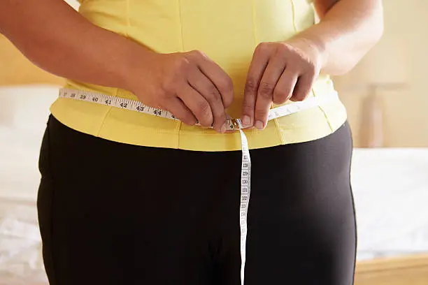 Close Up Of Overweight Woman Measuring Waist Gaining Weight