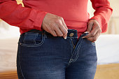 Close Up Of Overweight Woman Trying To Fasten Trousers
