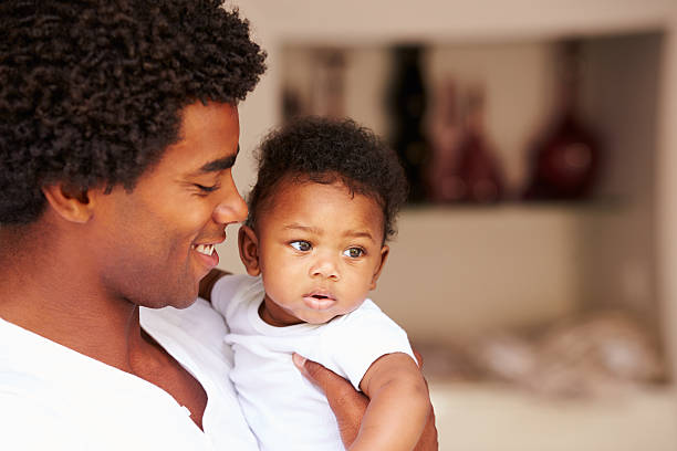 istock Dad Cuddling Baby Son At Home 506933353