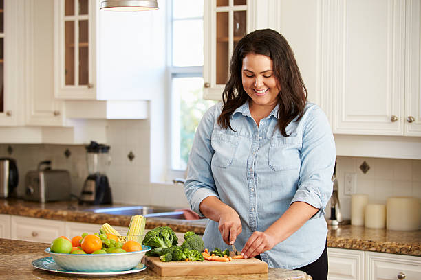 istock Overweight Woman Preparing Vegetables in Kitchen 506933629