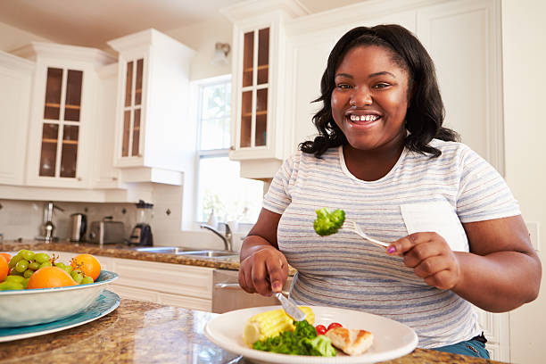 übergewichtige frau essen gesunde mahlzeit in der küche - fett nährstoff stock-fotos und bilder