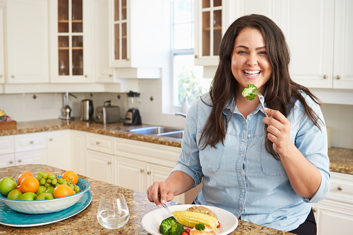 Gordo mujer comiendo comida saludable en la cocina photo