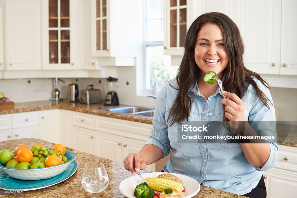 Femme en surpoids mangeant repas équilibré dans la cuisine - Photo de Surpoids libre de droits