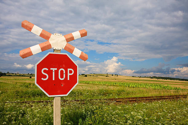 istock Stop sign in front of the railway, under cloudy sky. 506935281