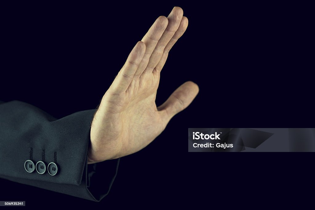 Man raising his hand in a stop gesture Retro image of man in a suit raising his hand in a stop gesture showing he has had enough or calling a halt or fending off something or someone against a dark background with copyspace. Adult Stock Photo