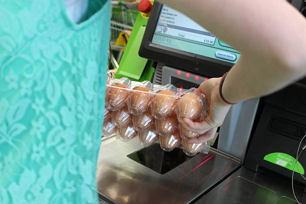 Girl scanning shopping (eggs) at self-service supermarket checkout till (self-checkout) Photo showing a girl scanning her shopping (including free-range eggs) at a self-service supermarket checkout till (also known as 'Self Checkouts' and 'Semi Attended Customer Activated Terminals' - SACAT.  Self-service checkouts are quickly becoming commonplace in large supermarkets, reducing staff costs and replacing the need for cashiers. self checkout stock pictures, royalty-free photos & images