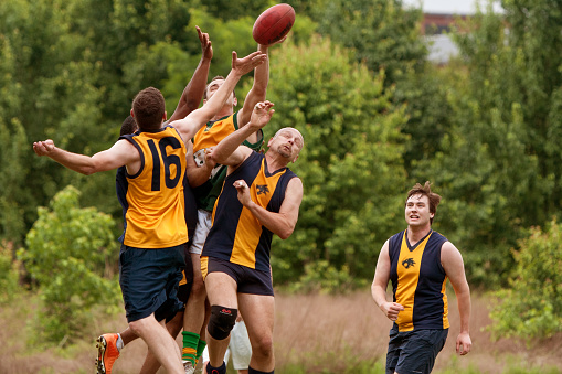 Roswell, GA, USA - May 17, 2014:  Several players jump to catch ball in an amateur club game of Australian Rules Football in a Roswell city park.