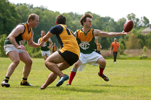 Roswell, GA, USA - May 17, 2014:  A player reaches to catch the ball on the run in an amateur club game of Australian Rules Football in a Roswell city park.
