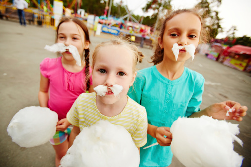 Image of funny girls with cotton candy posing on playground outdoors