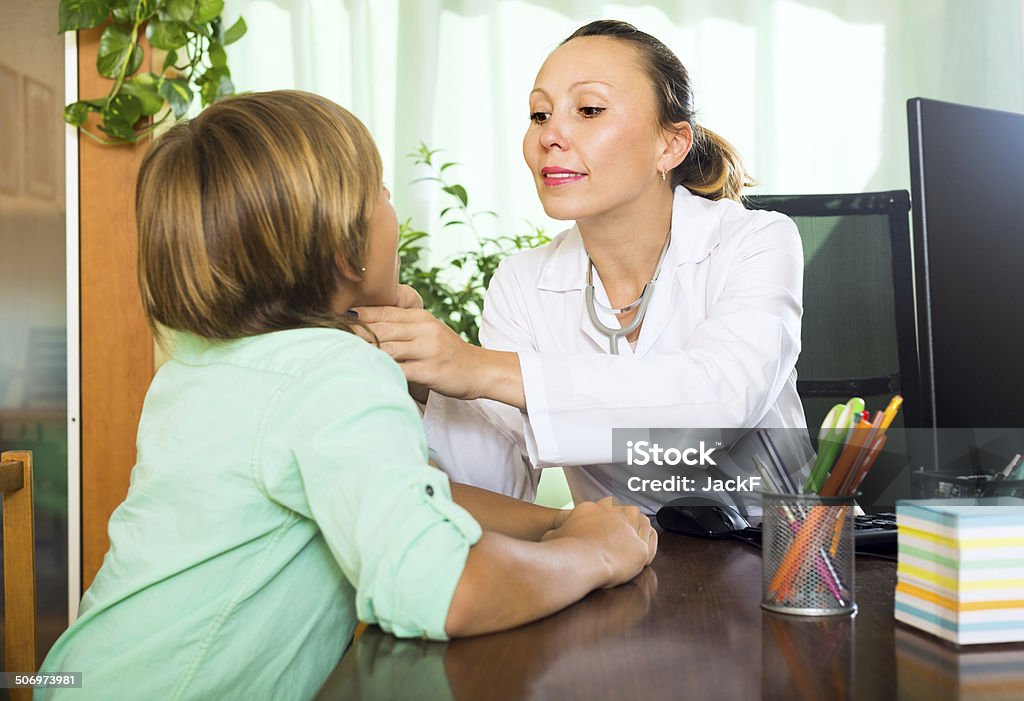 Doctor checking thyroid of teenager Friendly female doctor in clinic checking thyroid of teenager boy 10-11 Years Stock Photo