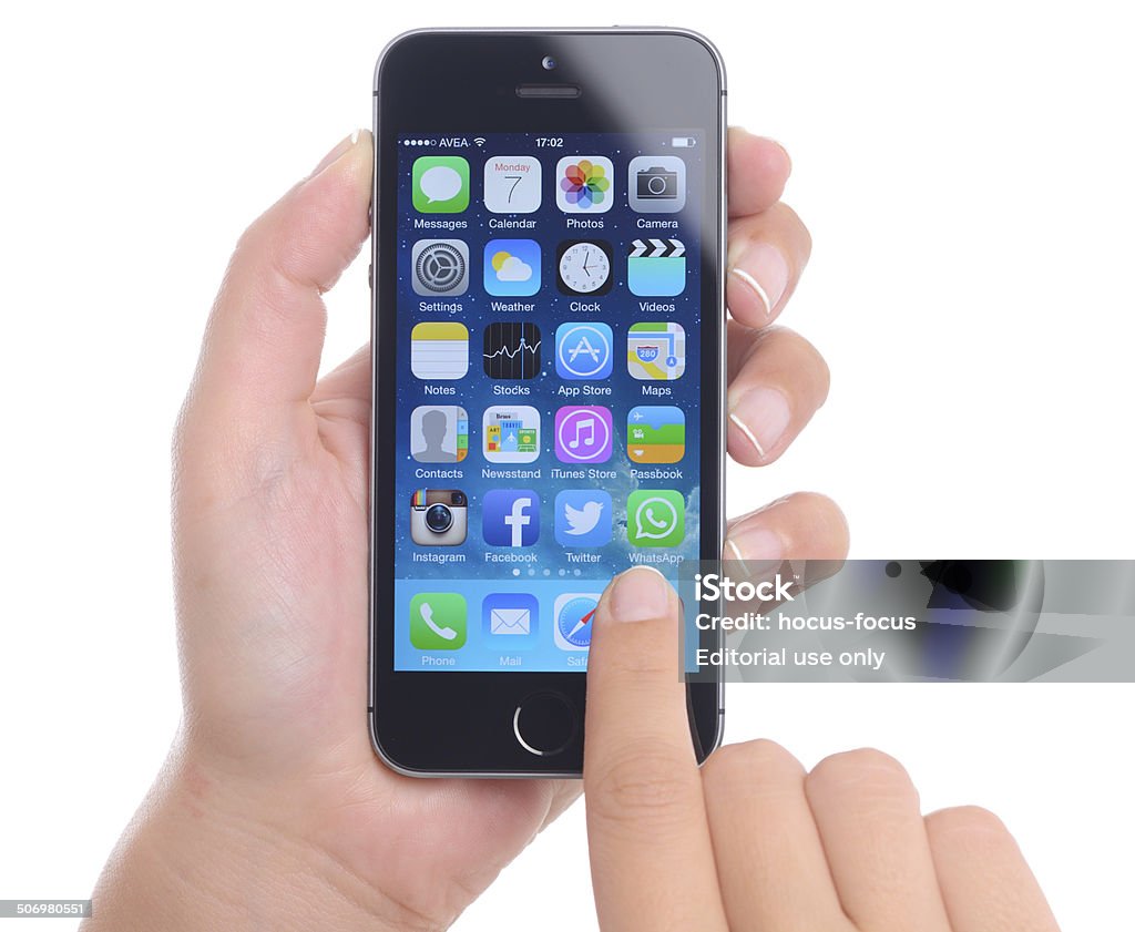 Hand holding iPhone 5s İstanbul, Turkey - July 7, 2014: Hands holding and touching iPhone 5s displaying home screen on a white background. The iPhone 5s is a touchscreen smartphone developed by Apple Inc. Cut Out Stock Photo
