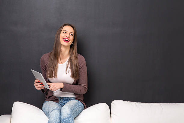 istock Girl sitting on a couch with a tablet 506989236