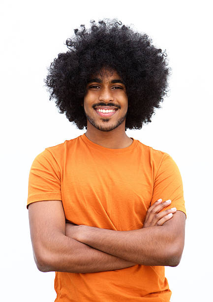 noir homme souriant avec bras croisés contre fond blanc - coiffure afro photos et images de collection