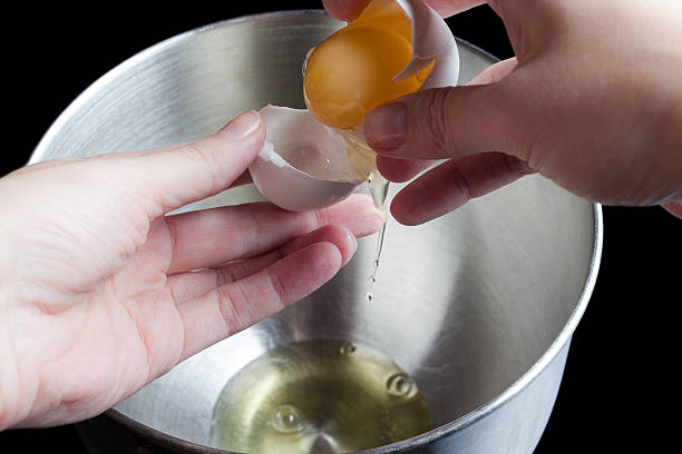 istock Pouring yolk from shell to shell above metal bowl 506990550