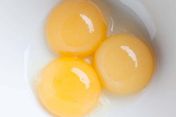 istock Three yellow fresh yolks in white bowl 506991204