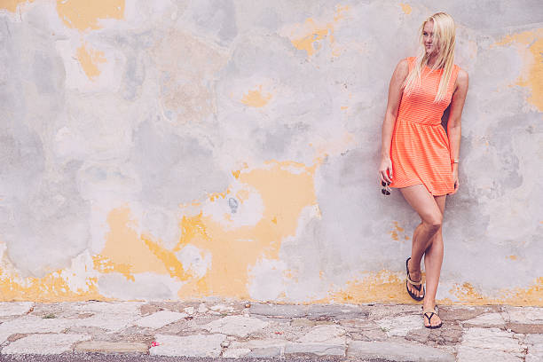 Portrait of a young beautiful caucasian blonde woman leaning against wall, looking away, copy space