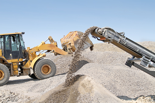 Pay loader and rock crusher at work on a road construction site. 