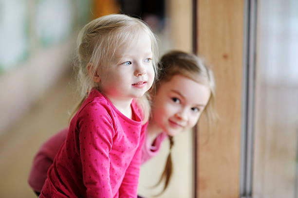 istock Two adorable little sisters by the window 506996658