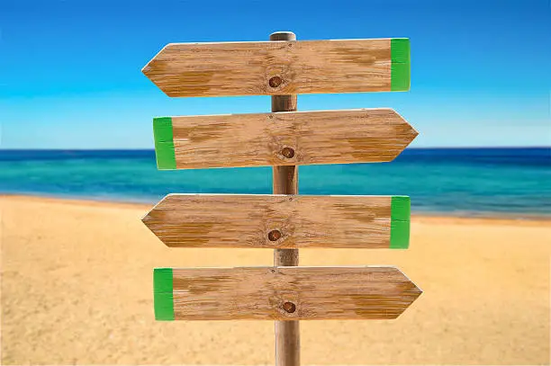 wooden signpost in the meadow with copyspace on the beach