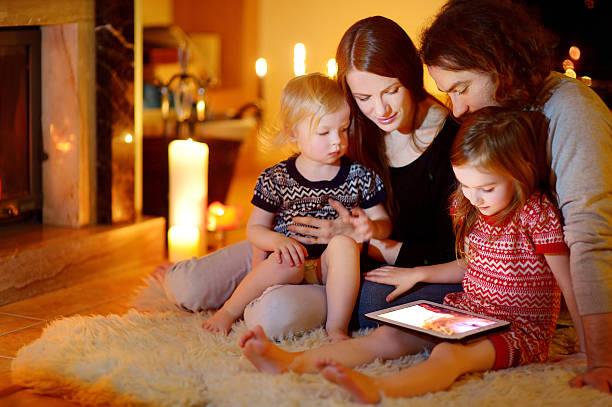 famiglia felice utilizzando tablet pc da un caminetto - home decorating living room luxury fireplace foto e immagini stock