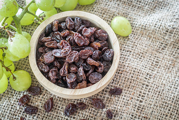 istock Raisins in bowl with grapes on table 507000830
